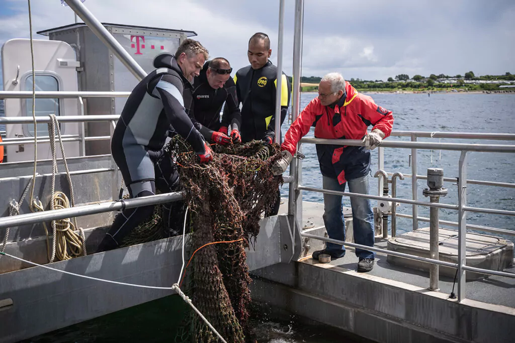 Taucher bergen ein großes Schleppnetz vom Meeresgrund. Foto: Oceanwell, Nikolas Linke